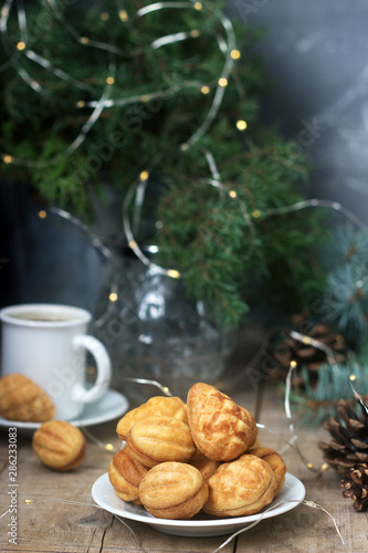 Homemade shortbread cookies in various shapes, filled with caramel on the background of fir branches and garlands.