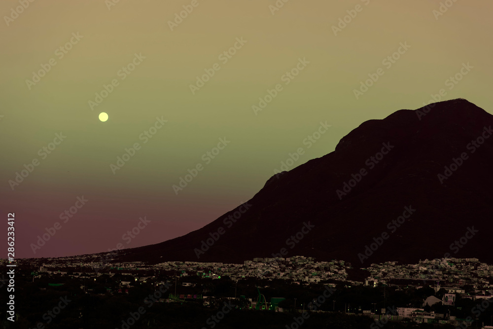 City lights in the evening with moon light in the big mountain in Monterrey, Mexico