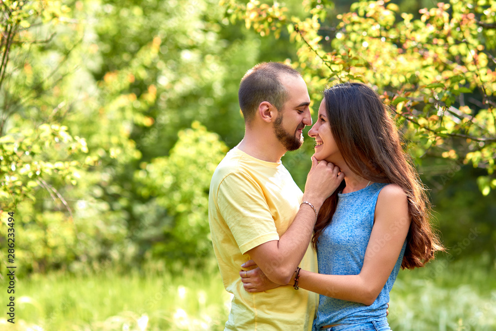 Fototapeta premium Lovers. A young couple. The guy with the girl are walking in the forest. Loving couple hugs sensually. Lovers man and woman in the arms of each other. Romantic walk in the forest. Loving relationship