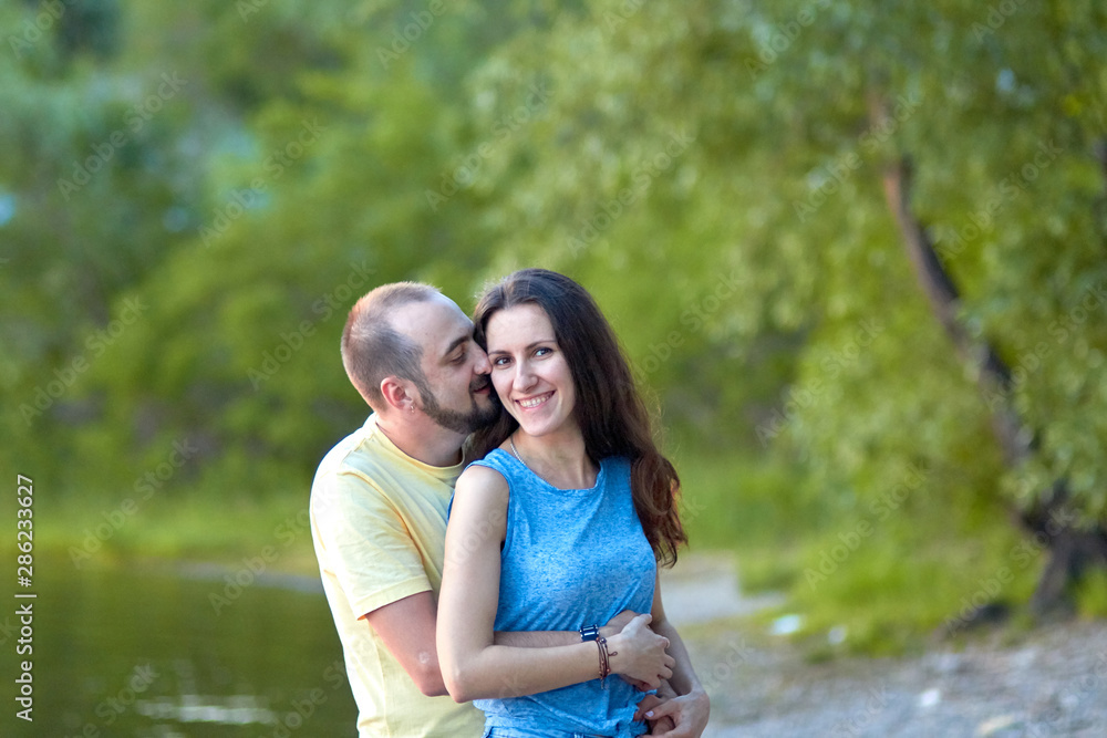 Fototapeta premium Lovers. A young couple. The guy with the girl are walking in the forest. Loving couple hugs sensually. Lovers man and woman in the arms of each other. Romantic walk in the forest. Loving relationship