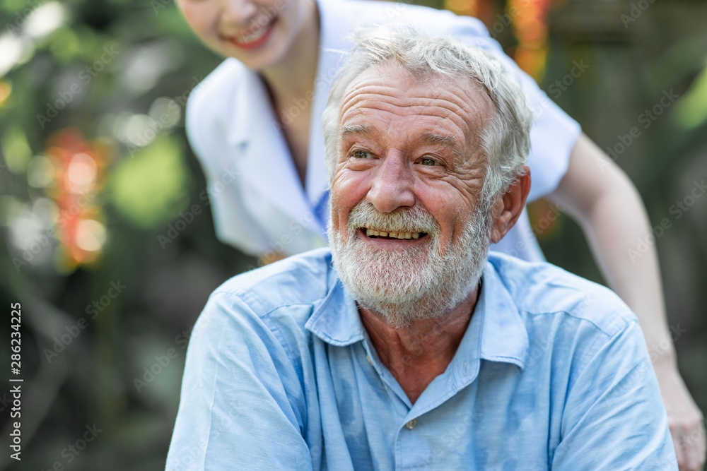 Caring nurse helping senior man sitting on wheelchair in gaden. Asian woman, caucasian man. Happy smile. Caring nurse helping senior man sitting on wheelchair in gaden. Asian woman, caucasian man. Happy smile.