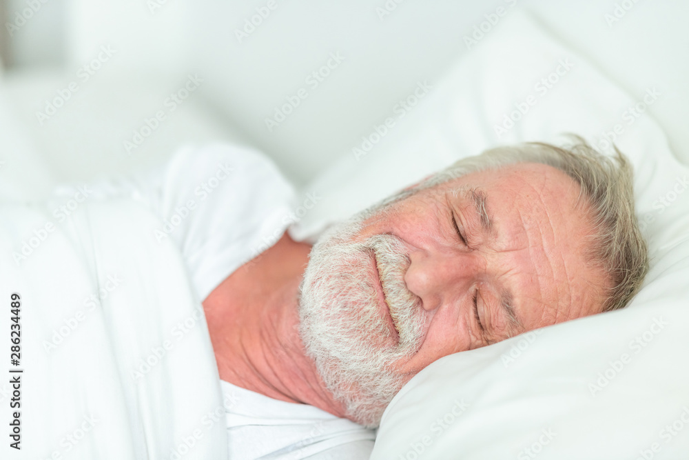 Happy senior man sleeping in bed.