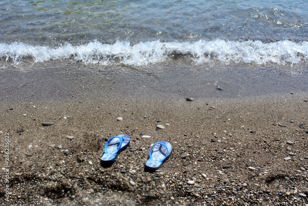 Obraz premium flips flop by the sea on the sand, near the water. Concept - beach vacation, sea vacation
