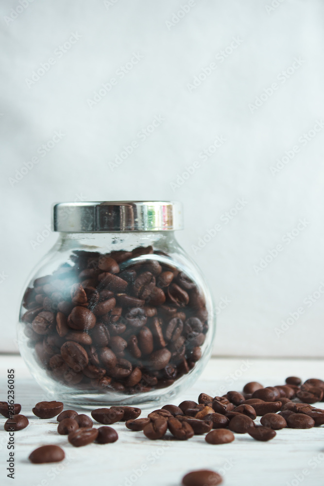 Coffee beans in a glass jar on a light wooden background Coffee beans in a glass jar on a light wooden background