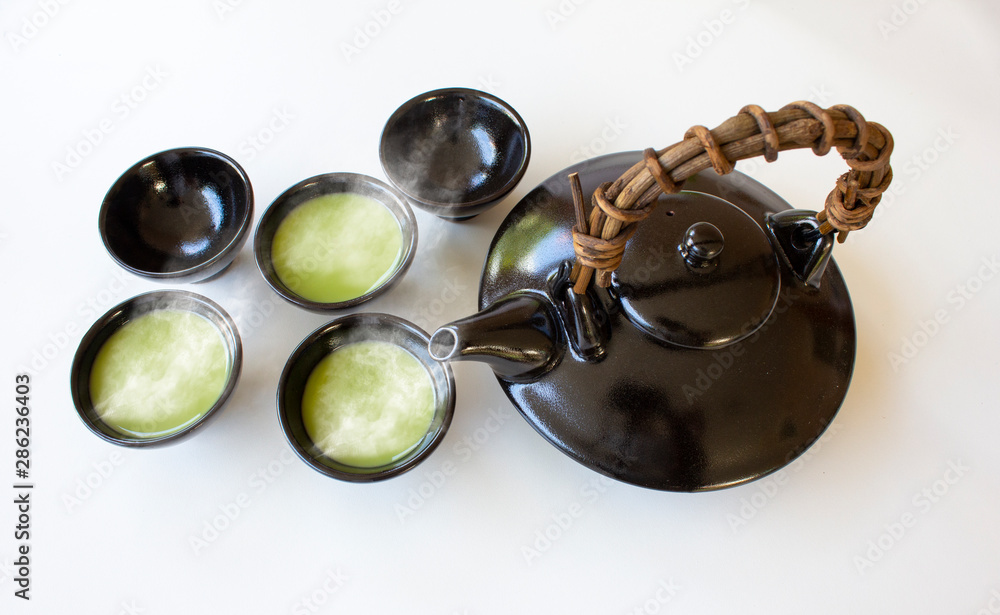 Asian clay teapot with hot green tea bowls on white background,Asian culture concept,