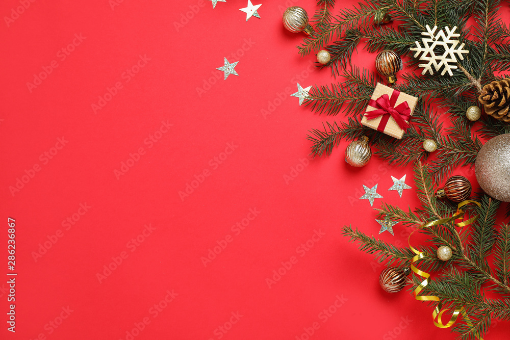 Fir branches with Christmas decoration on red background, flat lay. Space for text