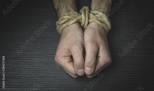 Male hands tied with a rope.