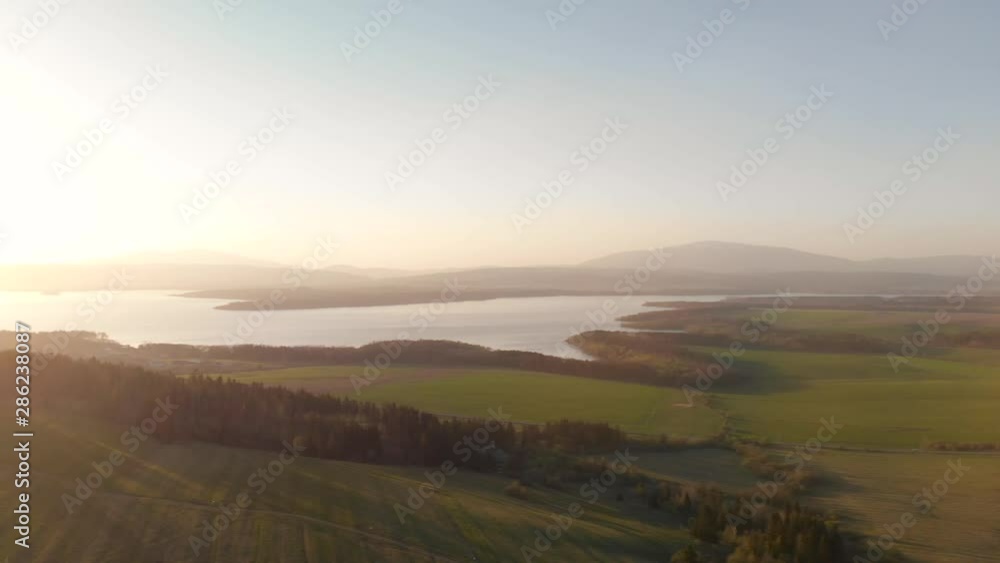 Right rotating aerial of beautiful sunflooded landscape with lake in distance and sun glares Right rotating aerial of beautiful sunflooded landscape with lake in distance and sun glares