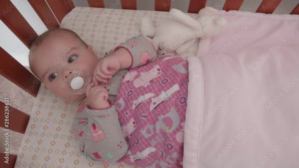 A slow motion dolly shot of a cute baby girl with beautiful eyes lying in crib A slow motion dolly shot of a cute baby girl with beautiful eyes lying in crib