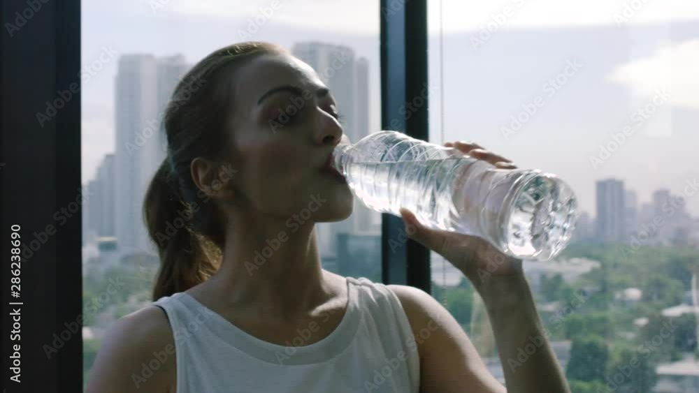 Woman drinking water after sport with the city of Manila in the background. The woman has red hair and red lipstick - sport concept Woman drinking water after sport with the city of Manila in the background. The woman has red hair and red lipstick - sport concept