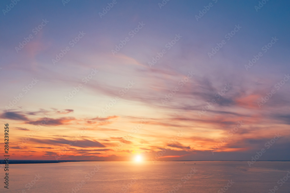 Skyline with a bright sunset in warm colors and picturesque high clouds over the bay, aerial view.
