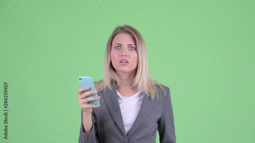 Face of stressed young blonde businesswoman using phone and looking shocked Face of stressed young blonde businesswoman using phone and looking shocked