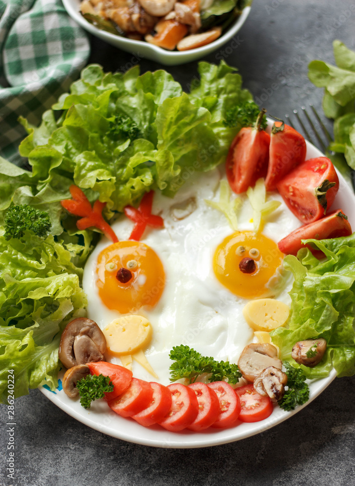 Kids breakfast with eggs and vegetables on a wooden table. Food art animal shaped eggs, funny creative idea Kids breakfast with eggs and vegetables on a wooden table. Food art animal shaped eggs, funny creative idea