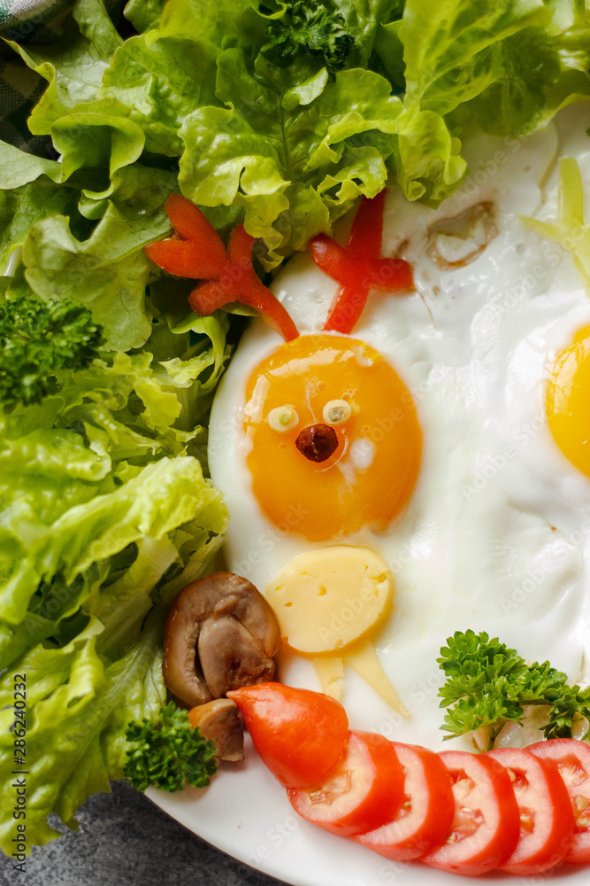 Kids breakfast with eggs and vegetables on a wooden table. Food art animal shaped eggs, funny creative idea Kids breakfast with eggs and vegetables on a wooden table. Food art animal shaped eggs, funny creative idea