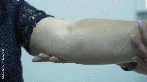 Close-up of pofessional caucasian female doctor checking arm of an elderly woman in the office. Mature lady went to the hospital with trauma. Concept of healthcare, treatment, medicine, recreation photo