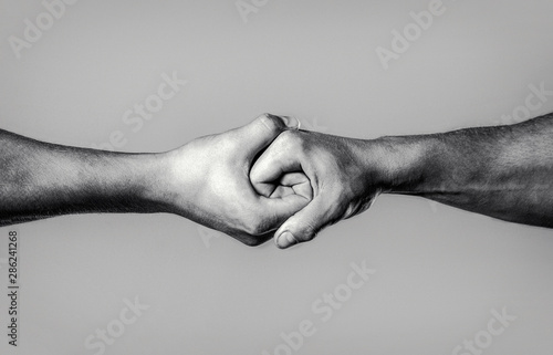 Two hands, isolated arm, helping hand of a friend. Rescue, helping hand. Male hand united in handshake. Man help hands, guardianship, protection. Black and white photo