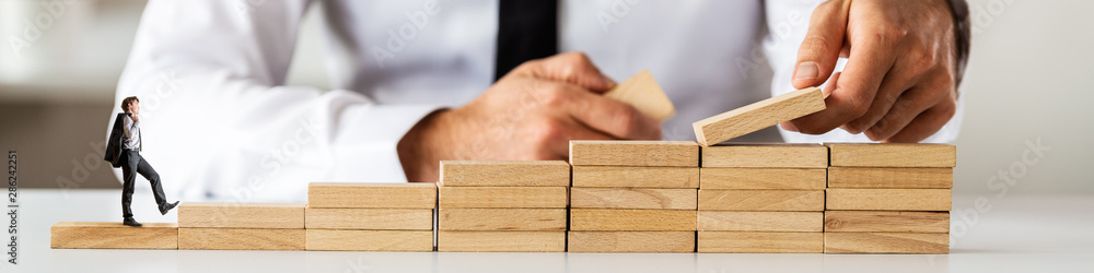 Wide view image of business adviser making staircase of wooden pegs