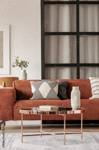 Stylish brown corner sofa with patterned pillows in elegant living room interior with mullions wall © Photographee.eu