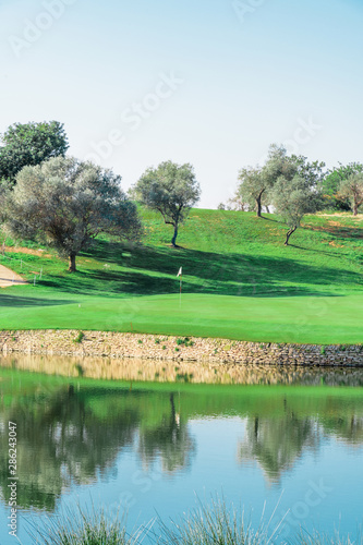 A beautiful lake with a golf course in the background and many trees in spring. Concept of tranquility on the course.