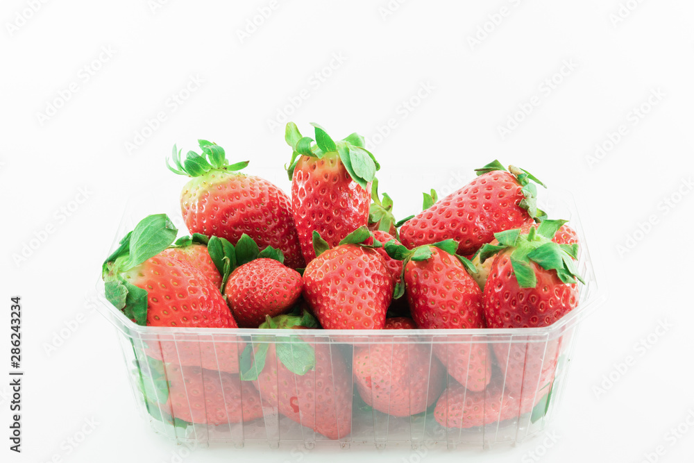 Fresh and delicious strawberries in a plastic tupper on a white background. Healthy food concept. Fresh and delicious strawberries in a plastic tupper on a white background. Healthy food concept.