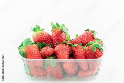 Fresh and delicious strawberries in a plastic tupper on a white background. Healthy food concept.