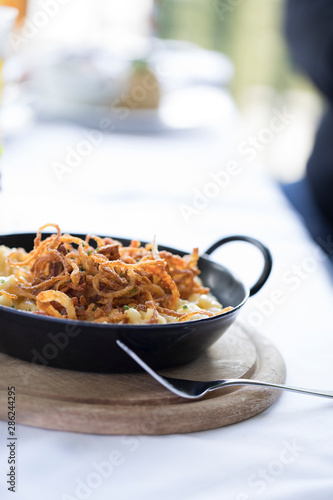 traditional alpine cheese dish in a iron pan served on a wooden board photo