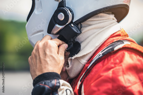 The racer's hand is wearing a helmet strap for safety in the race.