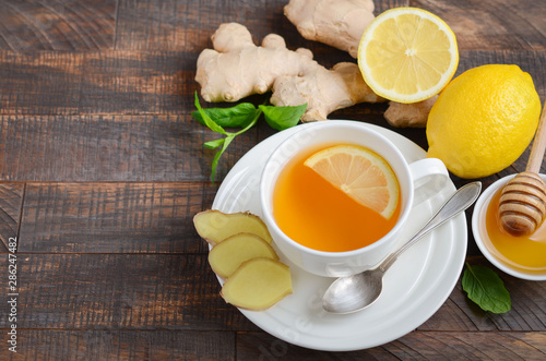 Ginger root tea with lemon and honey on wooden table.