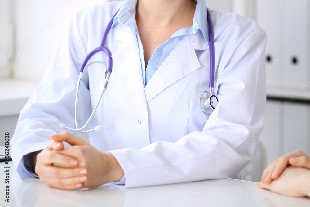Doctor and patient discussing something while sitting at the desk at hospital, close-up. Medicine and health care Doctor and patient discussing something while sitting at the desk at hospital, close-up. Medicine and health care