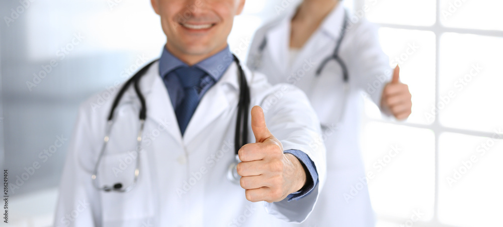 Group of doctors showing thumbs up. Perfect medical service in clinic. Happy future in medicine and healthcare concept