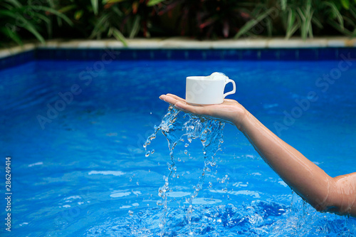 Young woman standing in pool with water. Girl scooping pool water