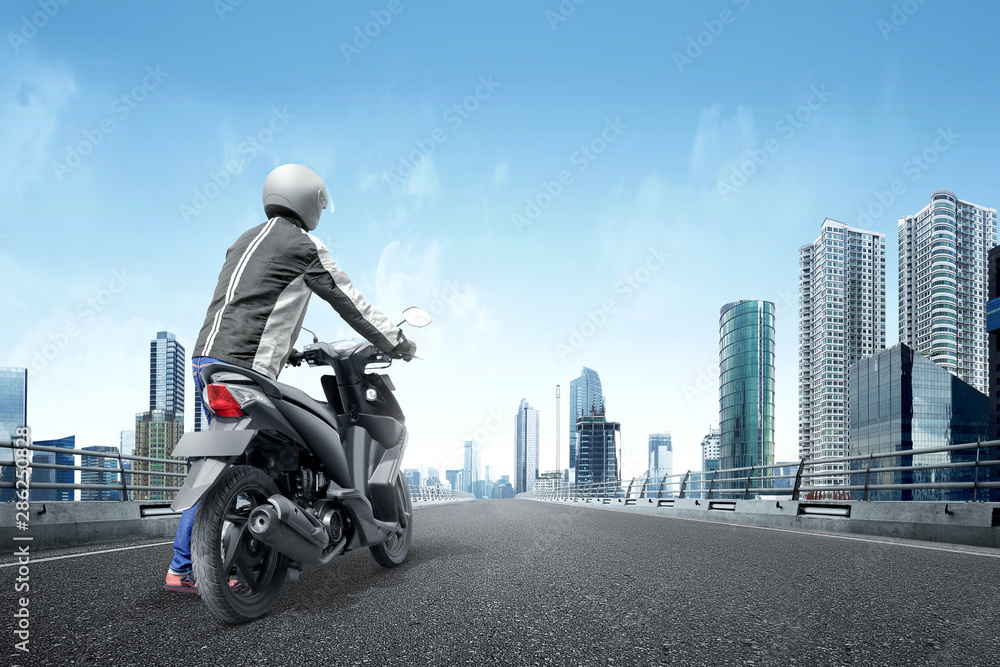 Rear view of Asian motorcycle taxi man pushes his motorcycle on the asphalt road Rear view of Asian motorcycle taxi man pushes his motorcycle on the asphalt road