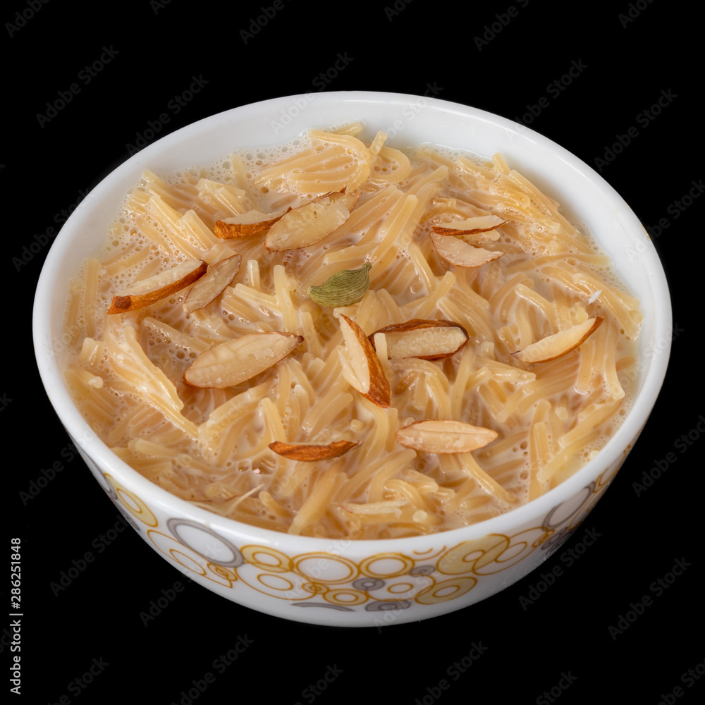 Vermicelli dessert, popular sweet dish know a kheer made with milk and garnish with dry fruits isolated on black gray background, served in bowl. Selective focus. Top view. Vermicelli dessert, popular sweet dish know a kheer made with milk and garnish with dry fruits isolated on black gray background, served in bowl. Selective focus. Top view.