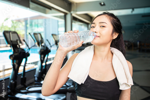 Women after exercise drink water from bottles and handkerchiefs in the gym.