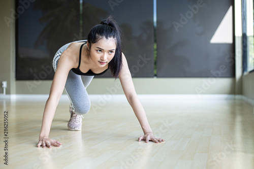 Young women warms up before exercising by pushing the floor and bending his knees in Gym.