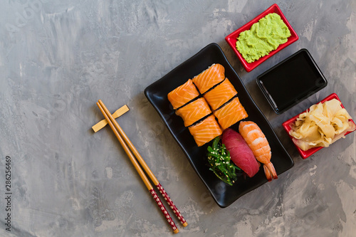 Top view on traditional japanese empty with sushi, ginger, soy sauce, wasabi bowl and chopsticks on concrete grey background, copy space, mockup, flat lay. Online asian food delivery concept
