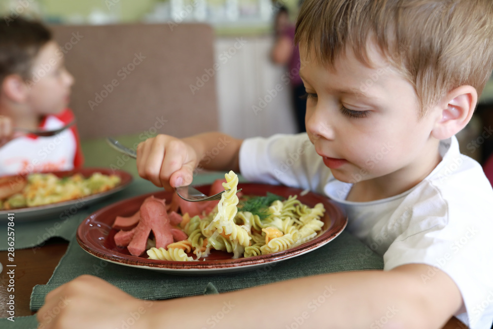 Child eating pasta with sausages