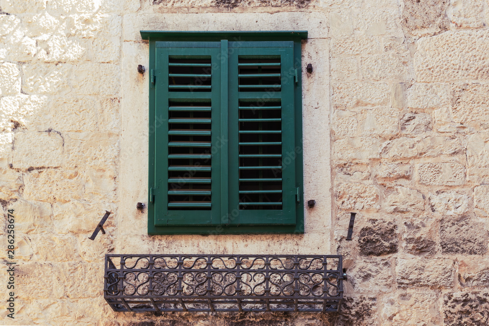 Window with green shutters on beige stone wall, beautiful old architecture of Split, Croatia