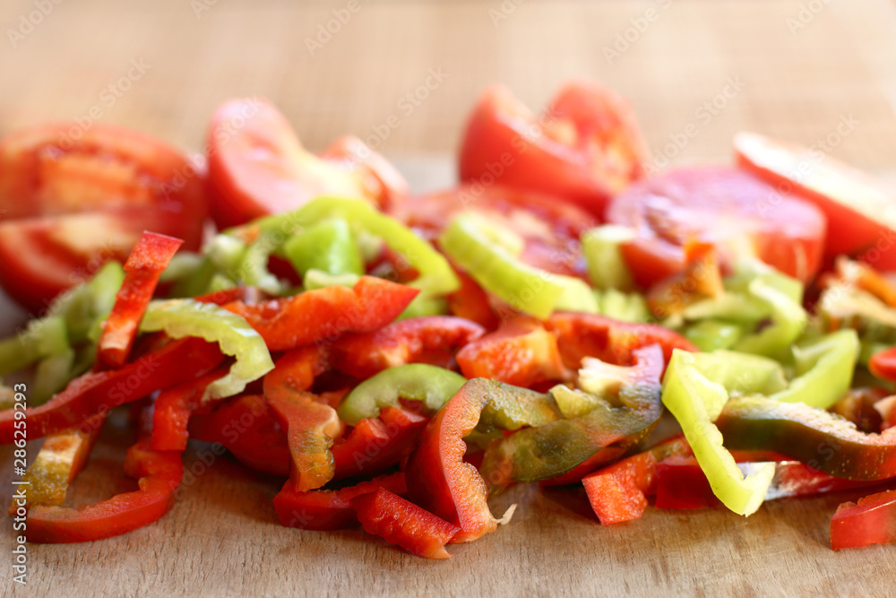 many slices of pepper and tomato on a cutting board front view. prepare a fresh salad of vegetables many slices of pepper and tomato on a cutting board front view. prepare a fresh salad of vegetables