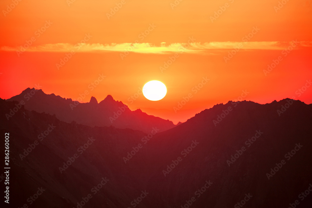 Sun over mountain ridges; beautiful colorful mountain sunset