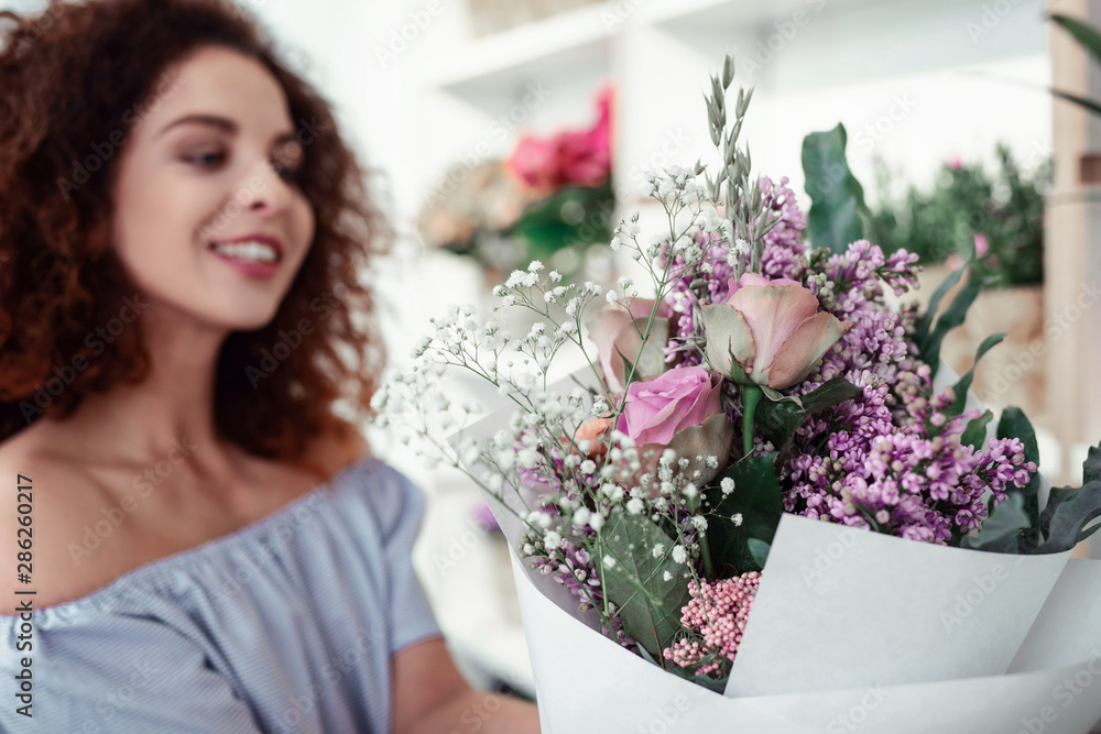 Smiling curly woman presenting results of her work in flower shop