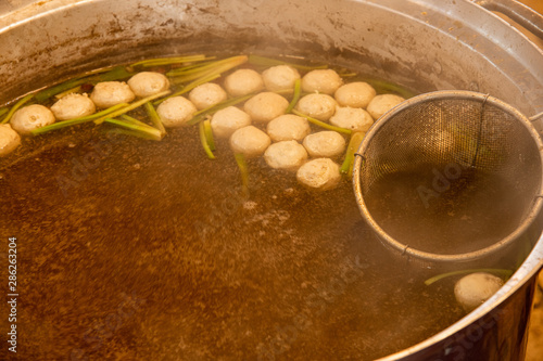 Meatballs with chicken stock hot soup in stanless steel Thai champer pot and noodle strainer, most popular noodle on street food in Thailand. photo