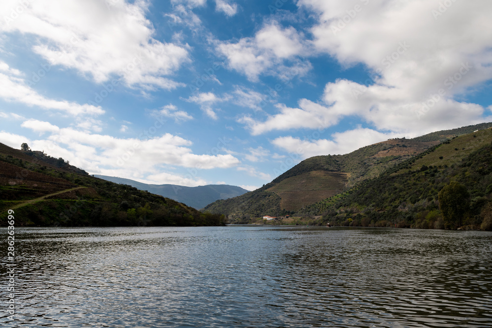 Scenic view of the Douro River with a traditional rabelo boat and terraced vineyards near the Tua village, in Portugal. Scenic view of the Douro River with a traditional rabelo boat and terraced vineyards near the Tua village, in Portugal.