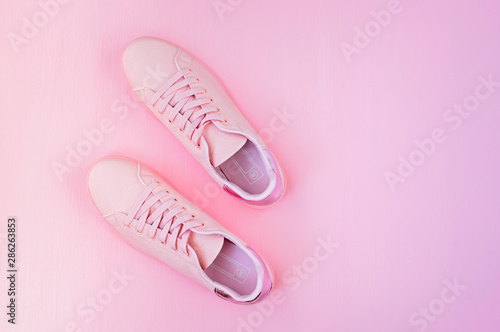 Pink women's sneakers on a pink background. Flat lay, minimal background, top view.