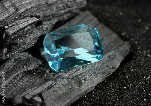 faceted blue jewelry gemstone aquamarine on black coal background photo
