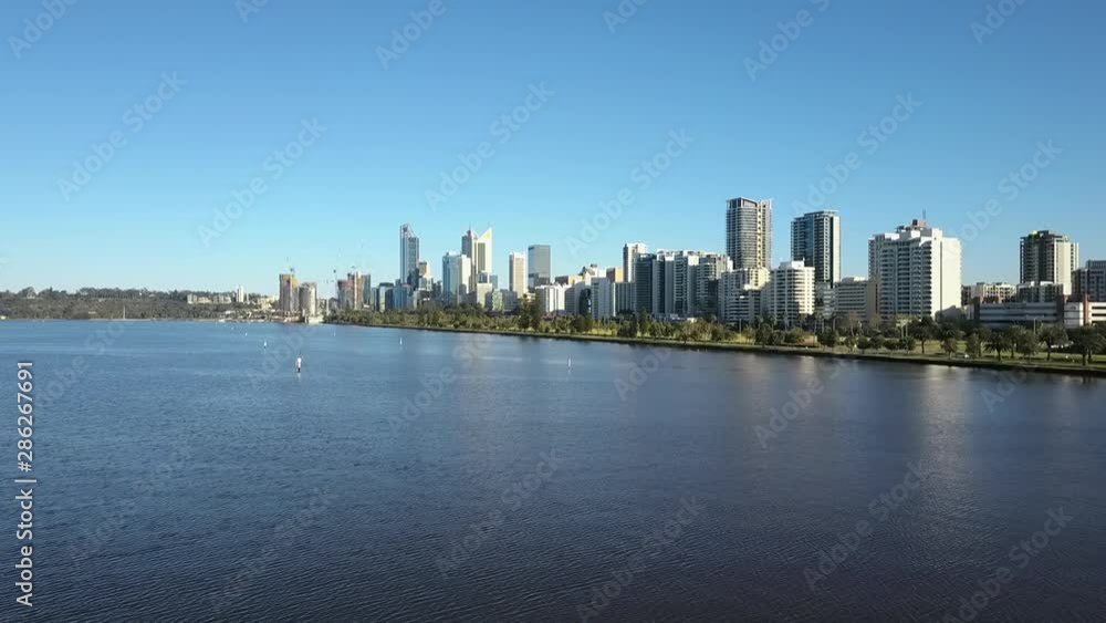 Beautiful scenic aerial view of drone flight above Swan River along the skyline of Perth, capital of Western Australia, with summer sunny blue sky and horizon as background. Beautiful scenic aerial view of drone flight above Swan River along the skyline of Perth, capital of Western Australia, with summer sunny blue sky and horizon as background.