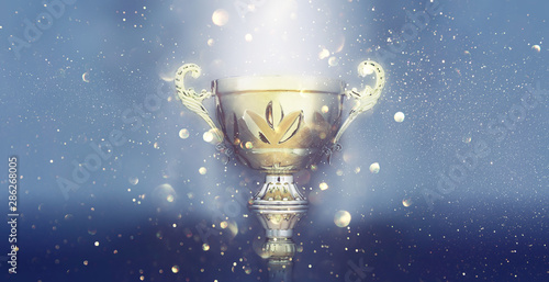 sports concept low key image of gold trophy over dark smoky background and glitter lights