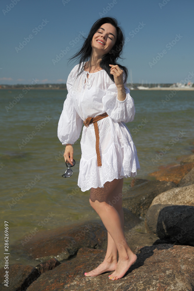 young happy girl in a white dress by the sea