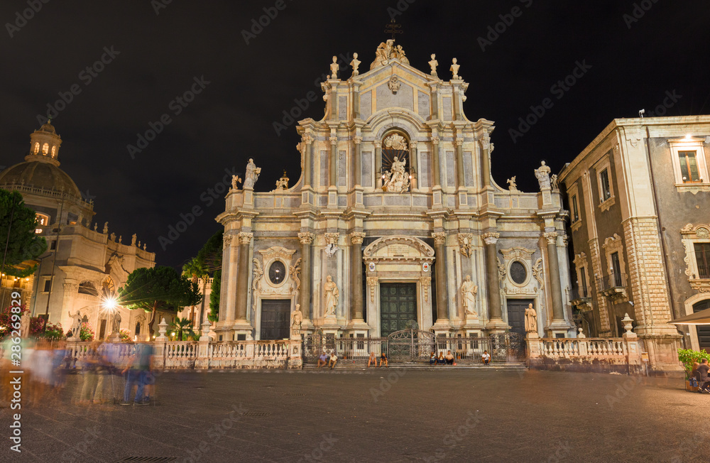 Night view of the crowded Duomo Square, with the baroque facade of the Cathedral of S. Agata in Catania in Sicily, Italy.