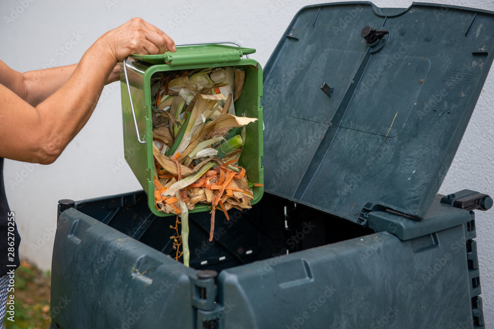 Tapet female emptying a bucketful of kitchen waste to the compost bin